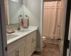 Double sinks in the hall bathroom with door, separating the vanity from tub and toilet