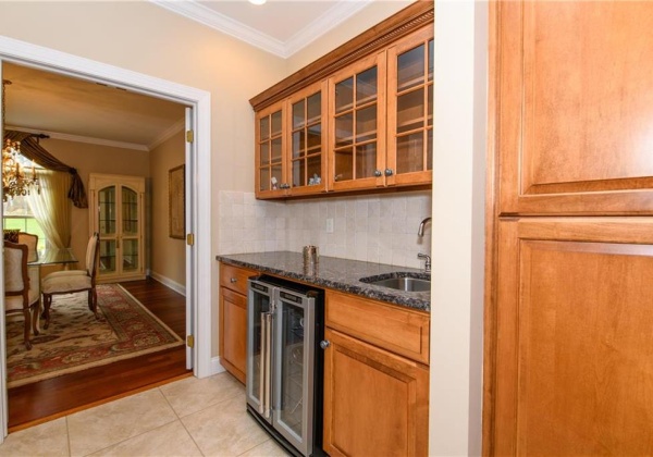 Wet bar between dining room and kitchen with wine refrigerator and sink