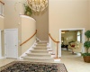 Foyer with chandelier, curved staircase and doors to den