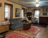 Living room with hardwood floors, many windows and two ceiling fans.