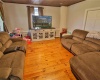 Large living room with refurbished wood floors and beadboard ceiling